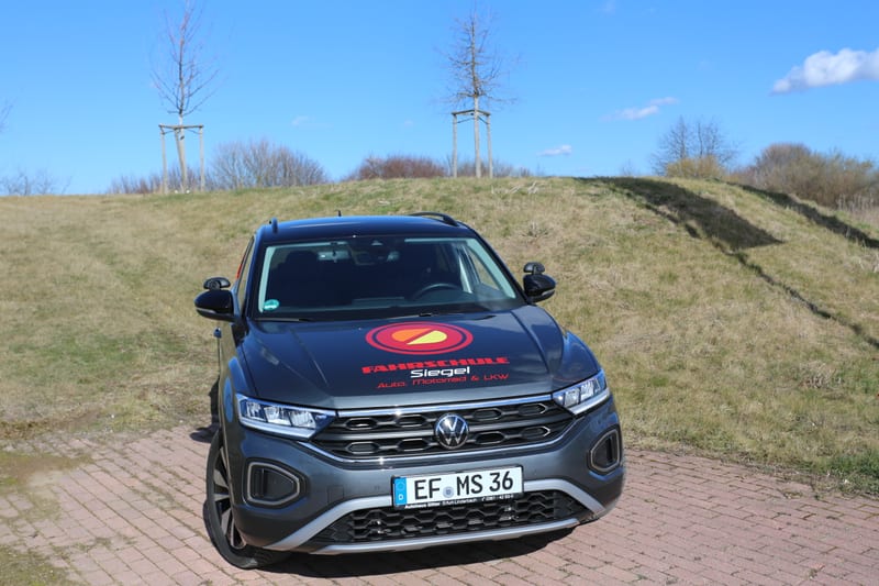 Grauer VW T-Roc der Fahrschule Siegel von vorn, Ausbildungsfahrzeug mit Schaltgetriebe